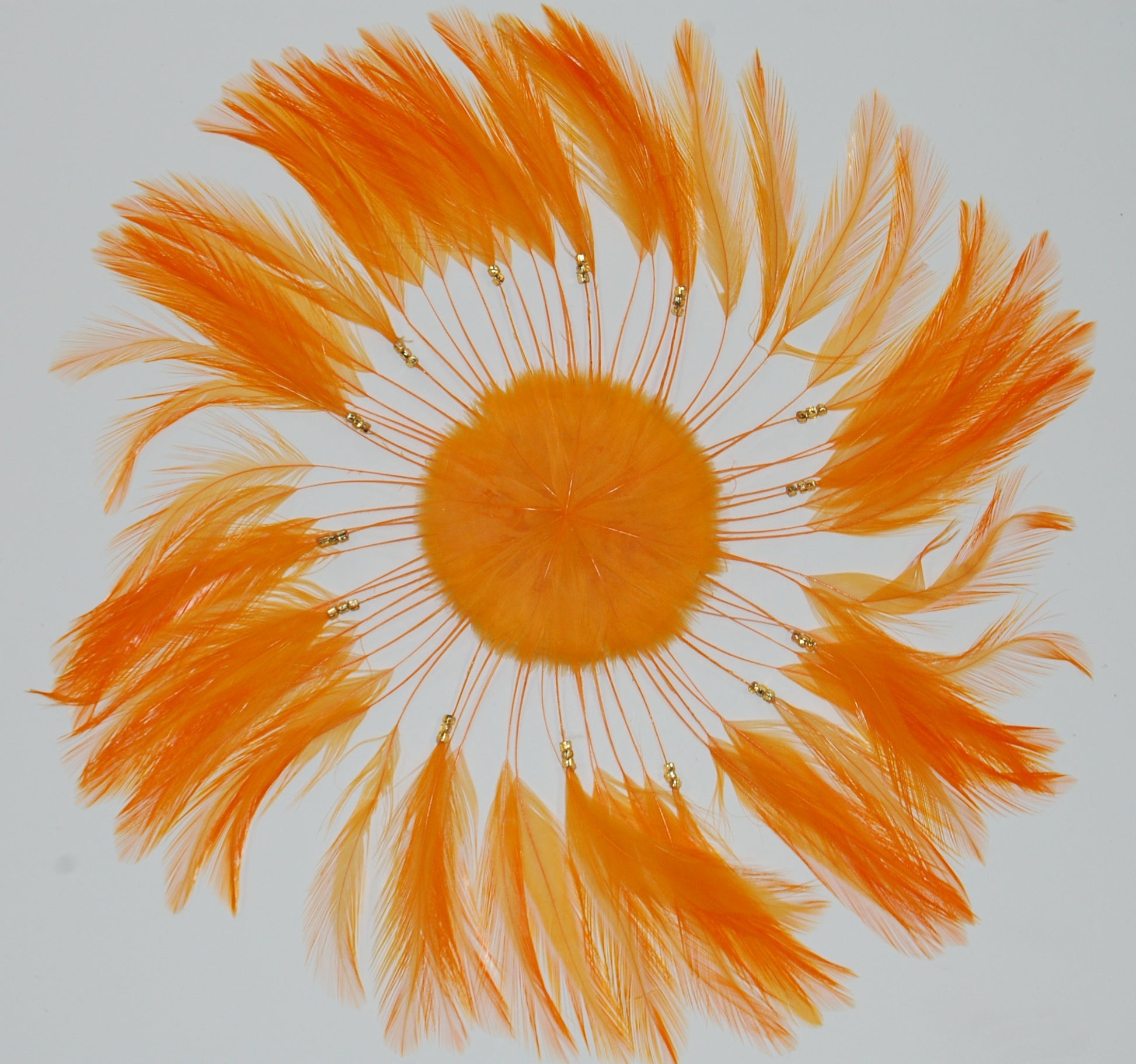 a tangerine colored feather pinwheel on white background